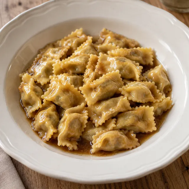 Agnolotti del plin con sfoglia sottile e sugo bruno d'arrosto in un piatto avorio