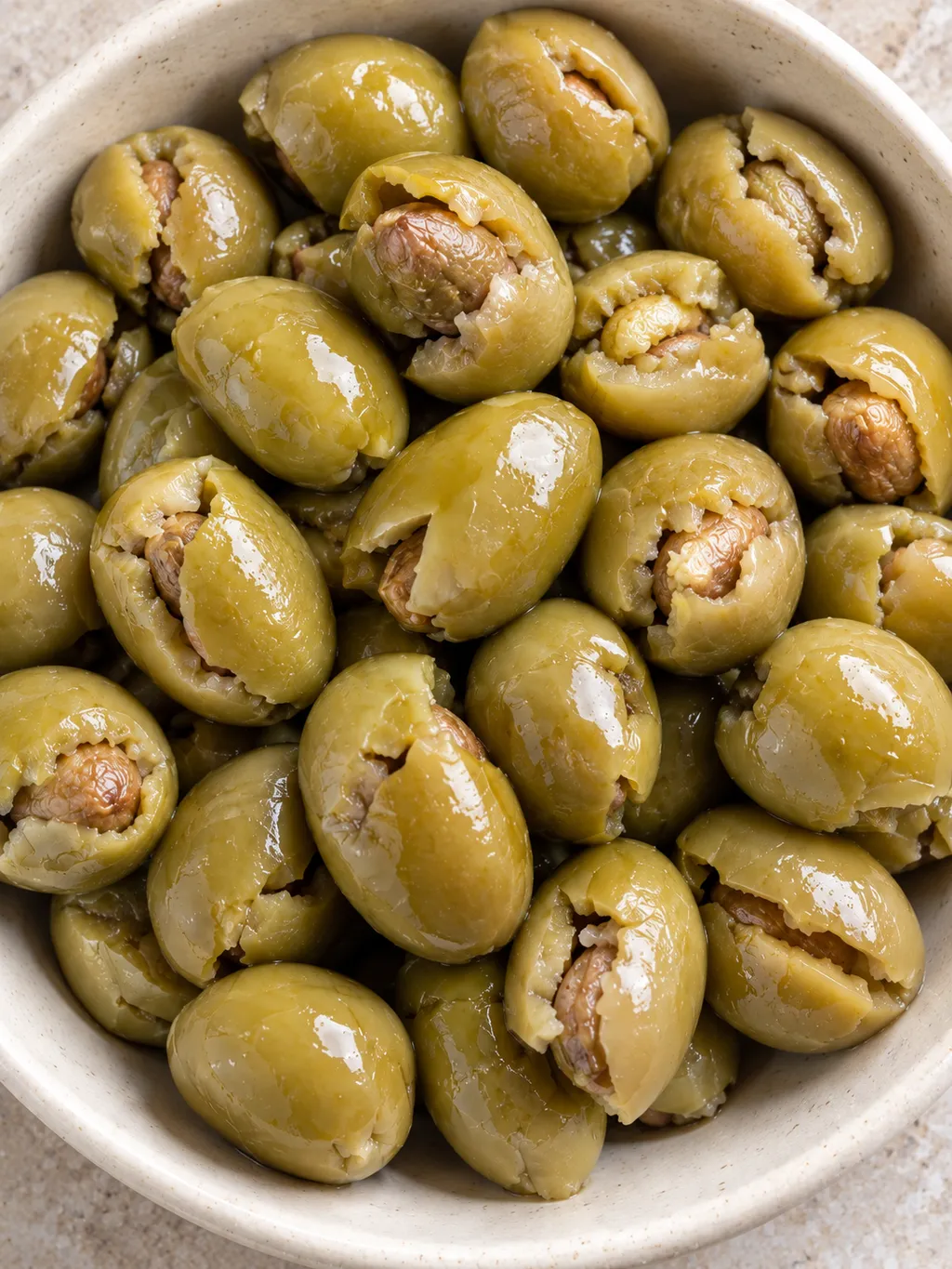Olive verdi schiacciate con polpa aperta e superficie umida, servite senza guarnizioni