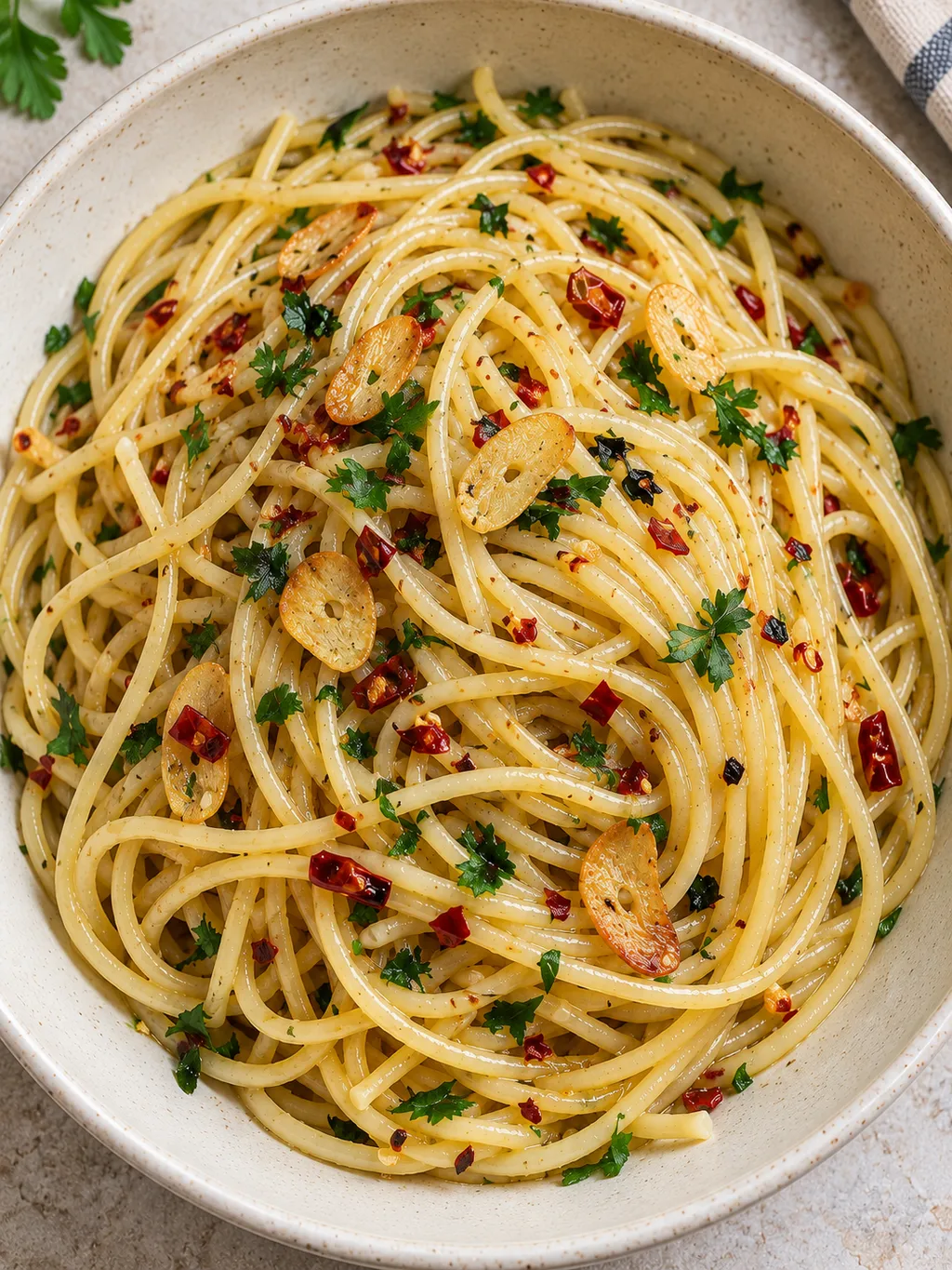 Spaghetti aglio, olio e peperoncino con prezzemolo in un piatto fondo avorio