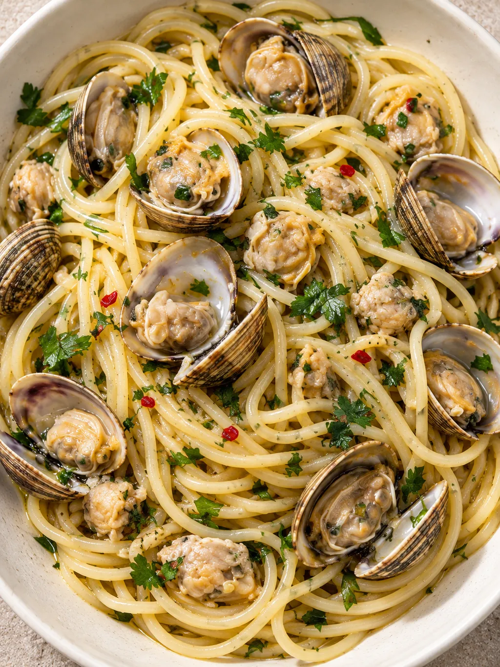Spaghetti lucidi con vongole sgusciate, gusci aperti e prezzemolo